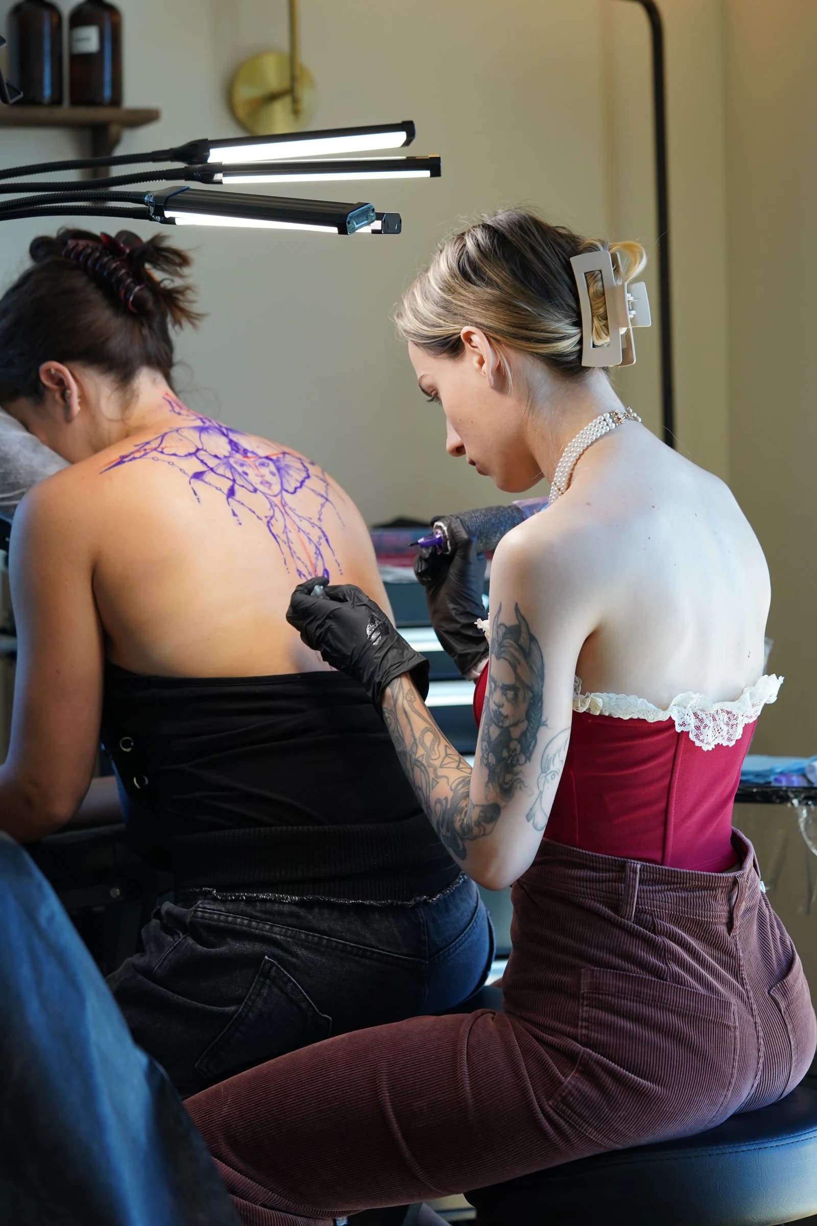 Nika Osseili tattooing a client's back in her studio.