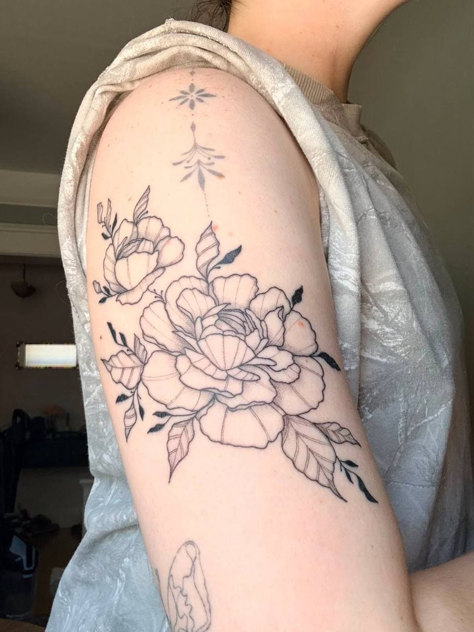 Healed botanical fine line flower tattoo on the upper arm by Nika Osseili.