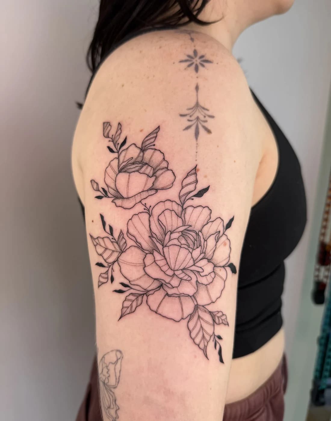 Close detail of a botanical shoulder tattoo by Nika Osseili.