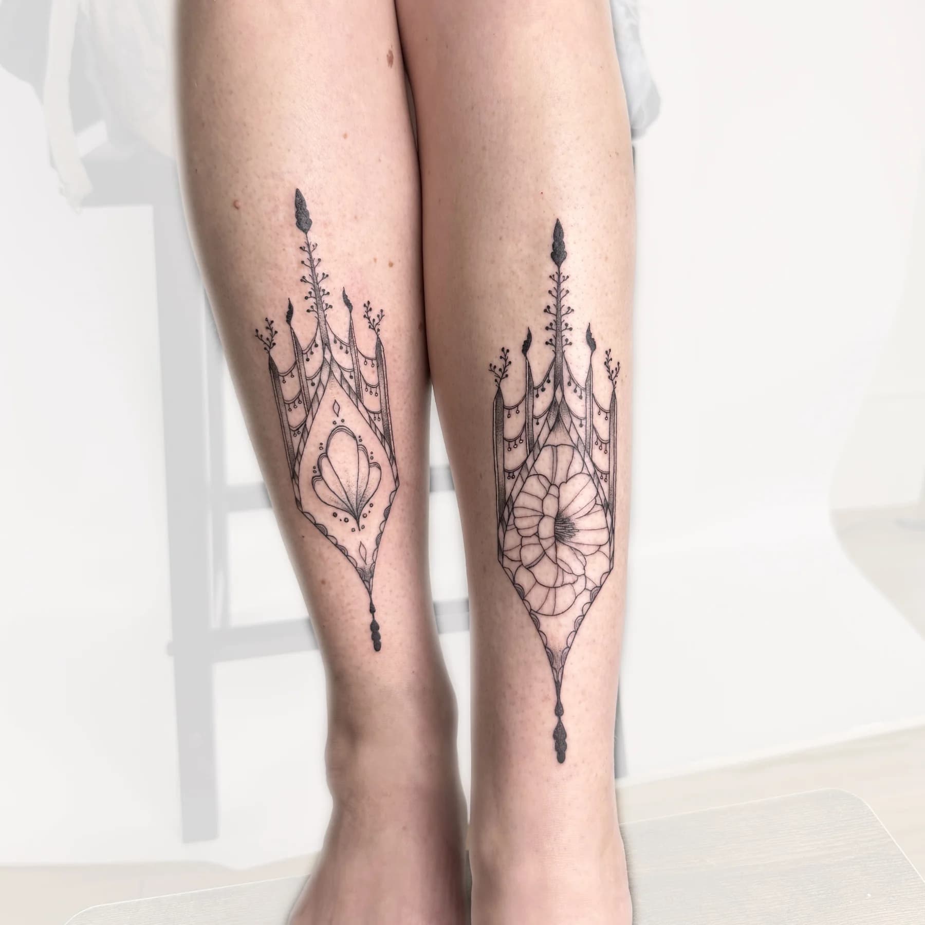 Paired ornamental architecture tattoos on the lower legs by Nika Osseili.