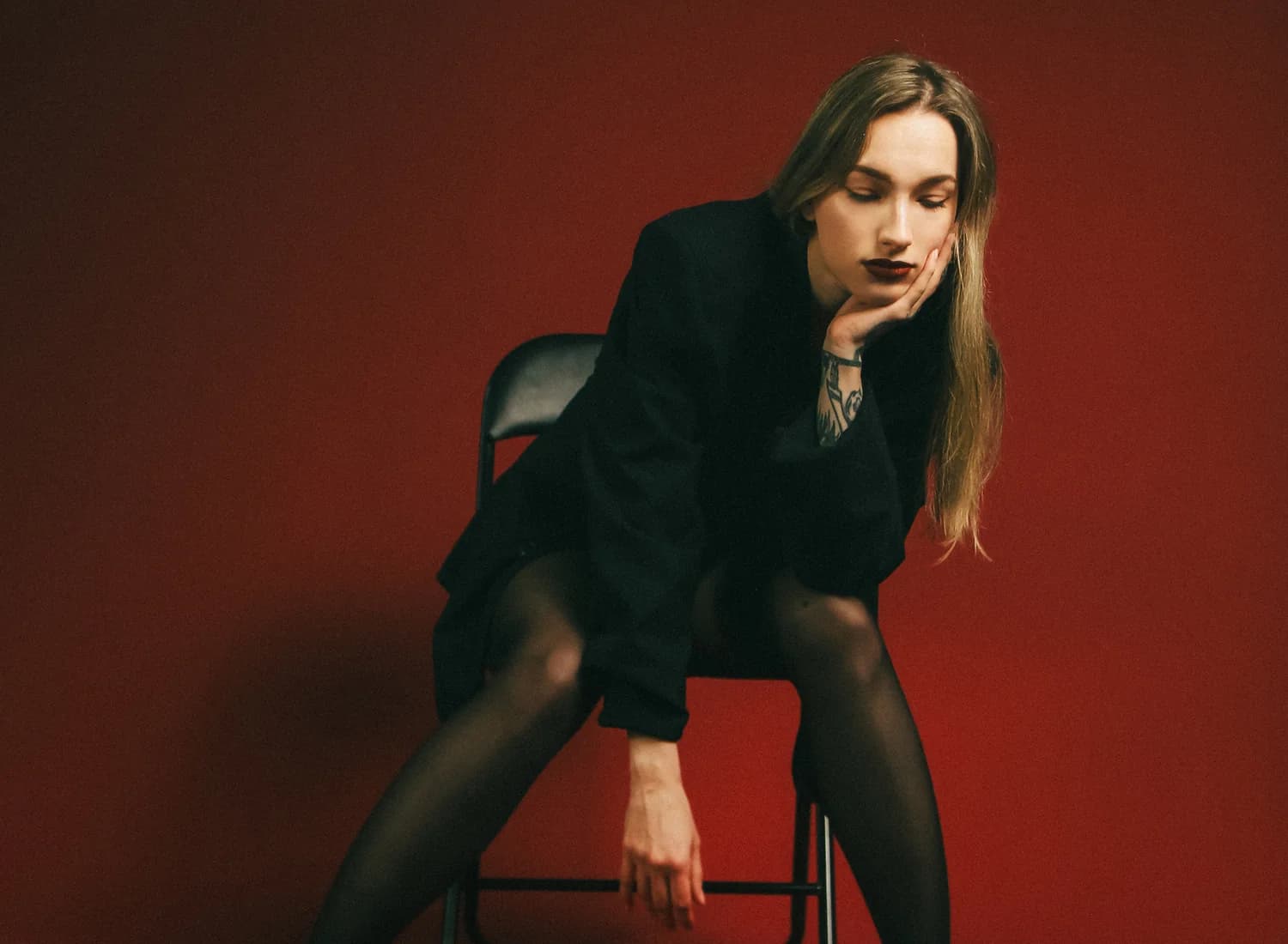 Editorial portrait of Nika Osseili seated on a red studio set.